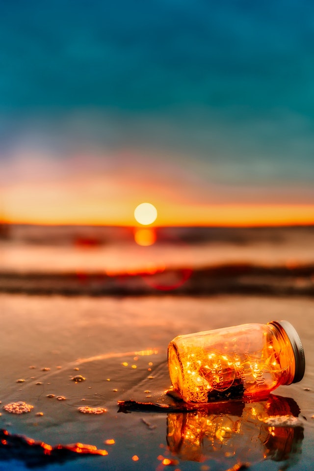 Zdjęcia z zachodem słońca z butelką nad morzem